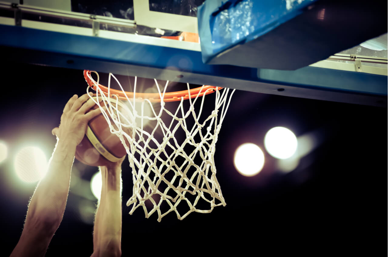 hands dunking basketball in hoop